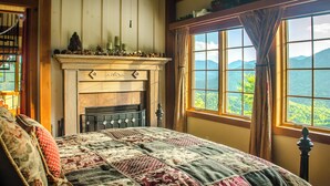 A bedroom with a large bed, a fireplace, and a window with a mountain view. - Hidden Gem in the Smokies - Awenasa (Franklin)
