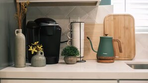 A kitchen counter with a Keurig coffee maker, a Keebar water kettle, a small potted plant, and a wooden cutting board. - Charming Detached Bungalow in Historic Old Town Monrovia Kingsize Bed！ (Monrovia)