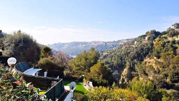 Eine Terrasse mit einer gewölbten Glasscheibe, Satellitenschüsseln und üppigem Grün.
