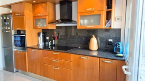 Eine moderne Küche mit Holzschränken, einem schwarzen Herd und einer Arbeitsplatte aus Granit.
