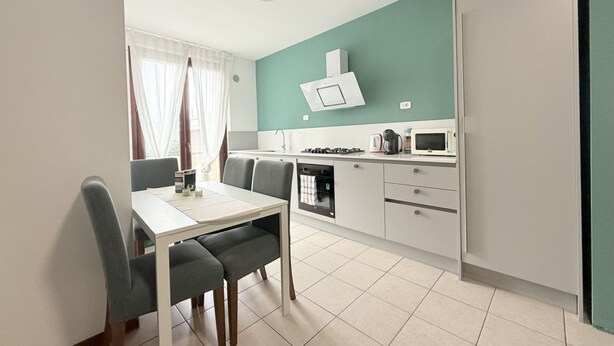 A compact kitchen with a dining area, a microwave, a gas stove, and a cabinet. - L'Ostro - Civitanova Marche, new two-room apartment in a strategic location (Civitanova Marche)