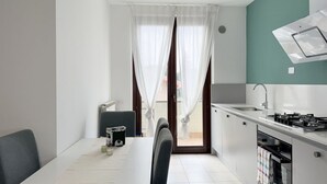 A compact kitchen with a dining area, a view through the window, and a modern stove. - L'Ostro - Civitanova Marche, new two-room apartment in a strategic location (Civitanova Marche)