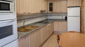 A compact kitchen with a sink, stove, microwave, and refrigerator. - Turisme Rural El Janpere - La Cabanya (Sant Joan de les Abadesses)