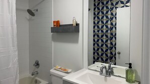 Ein Badezimmer mit Dusche, Toilette, Waschbecken und Spiegel.