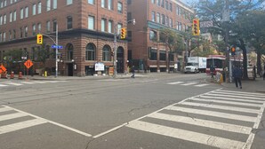 Eine Straßenscharte mit einem Backsteingebäude, Ampeln und einer Fußgängerampel.