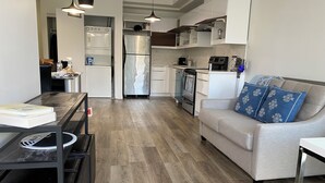 Eine moderne Küche mit weißen Schränken, Edelstahlgeräten und einem grauen Sofa mit blauen Kissen.
