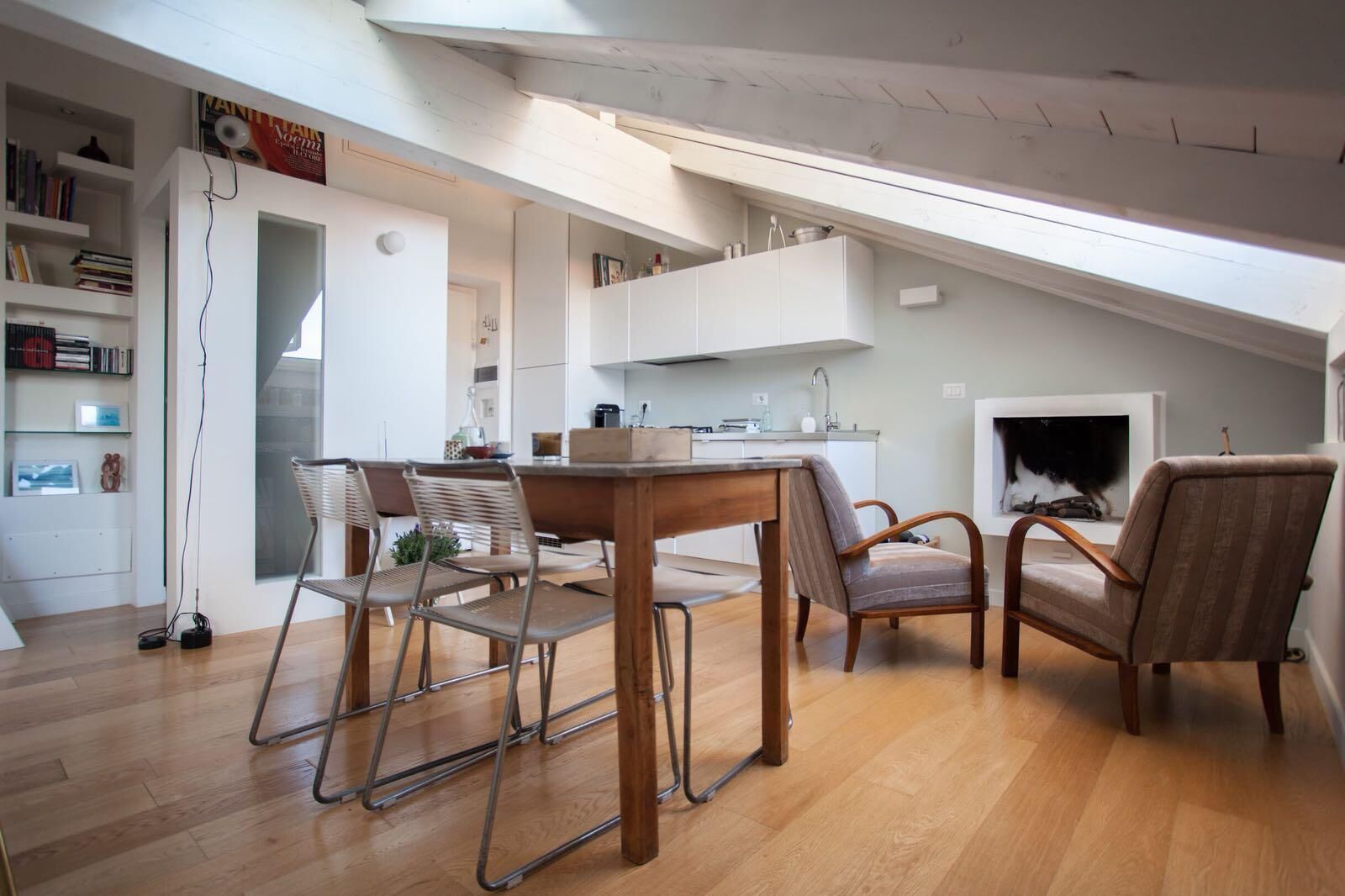A modern loft apartment with a dining area, kitchen, and a fireplace.