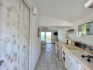 A kitchen with a stone floor, a large window, and a view of the sea. - Ostuni Green Hills Apt. 1 – Charming Home with Panoramic View & Shared Jacuzzi (Puglia)
