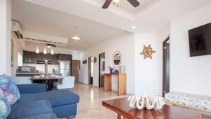 Un soggiorno moderno con un divano blu, un tavolino in legno e un'area pranzo con una cucina sullo sfondo.