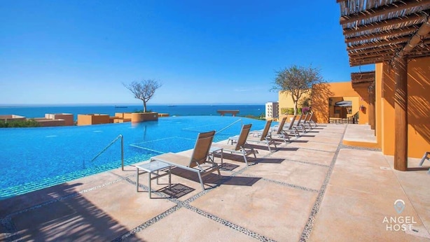 A poolside area with lounge chairs and a clear view of the ocean. - Exclusive Residential Living at Puerta Cortes (Lomas de Palmira)