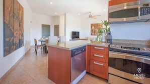 A modern kitchen with a central island, built-in oven, microwave, and dishwasher. - Exclusive Residential Living at Puerta Cortes (Lomas de Palmira)