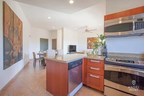 A modern kitchen with a central island, built-in oven, microwave, and dishwasher. - Exclusive Residential Living at Puerta Cortes (Lomas de Palmira)