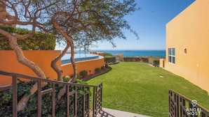 A property with a well-maintained lawn, a tree, and a view of the sea. - Exclusive Residential Living at Puerta Cortes (Lomas de Palmira)