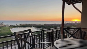 A balcony with a view of the sunset over a body of water, equipped with chairs and a table. - Exclusive Residential Living at Puerta Cortes (Lomas de Palmira)