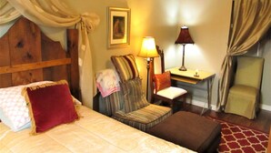 Una habitación de hotel con cama, una silla, una mesa y una lámpara.