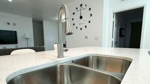 Une cuisine moderne avec un évier en acier inoxydable et une horloge murale.