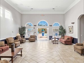 A spacious lobby with a tiled floor, multiple seating areas, and large windows offering views of the outdoors. - Family Condo Near Disney • Mickey, Mario & Harry P (Kissimmee)