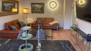 Ein modernes Wohnzimmer mit einer Sofagarnitur, einem Couchtisch, einer Lampe und gerahmten Kunstwerken an den Wänden.