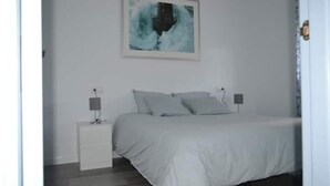 A bedroom with a bed, two bedside tables, and a wall-mounted artwork. - Rural house in the middle of nature (Chiclana de la frontera)