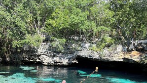 A clear, turquoise water body surrounded by rocky cliffs and dense greenery. - Luxury Studio & 1BR Condos • Pools • Near Tulum & Akumal Beaches (Akumal)