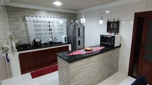 A compact kitchen with a central island, built-in appliances, and a red rug. - Complete house with a beautiful view of nature. (Bananal)
