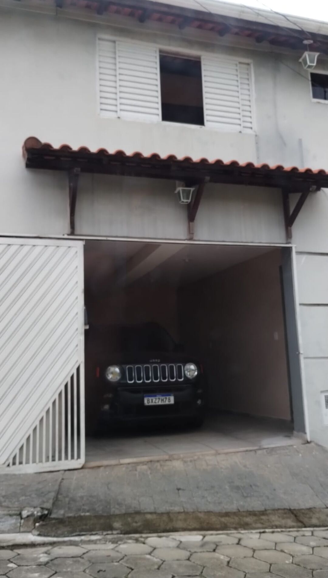 Un SUV nero parcheggiato in un garage con una porta bianca e un cancello in metallo.