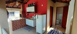 Una cocina compacta con horno de ladrillo, armarios blancos y un refrigerador.