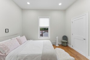 Une chambre à coucher avec un lit, une fenêtre, une porte et un petit tabouret.