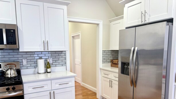 A modern kitchen with white cabinetry, stainless steel appliances, and a wooden floor. - Broadway Nomad House in Providence (Providence)