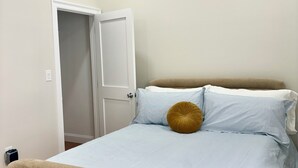 A bedroom with a bed, a door, and a light switch on the wall. - Broadway Nomad House in Providence (Providence)