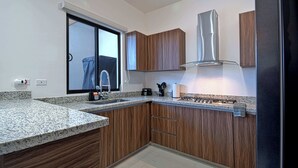 Uma cozinha moderna com armários de madeira, bancadas de granito, coifa de aço inoxidável e uma janela com vista.