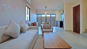 Uma sala de estar moderna com sofá, poltronas, mesa de centro e um espaço de jantar com mesa e cadeiras.