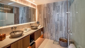 Une salle de bain moderne avec un grand miroir, deux vasques, des meubles en bois et une cabine de douche en verre.