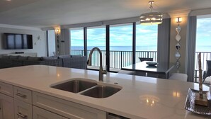 Een moderne keuken met een groot eiland, een eetgedeelte met uitzicht en een woonkamer met een flatscreen-tv.