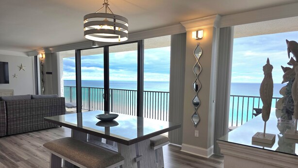 Een moderne eetruimte met een glazen tafel, een bank en uitzicht op zee.