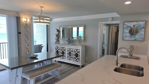 Een moderne keuken met een marmeren aanrecht, een inbouwspoelbak en een eethoek met een bank.