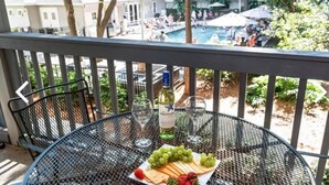Un balcon avec une table dressée pour un repas, donnant sur un espace piscine.