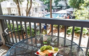 Un balcón con una mesa lista para una comida, con vista al área de la piscina.