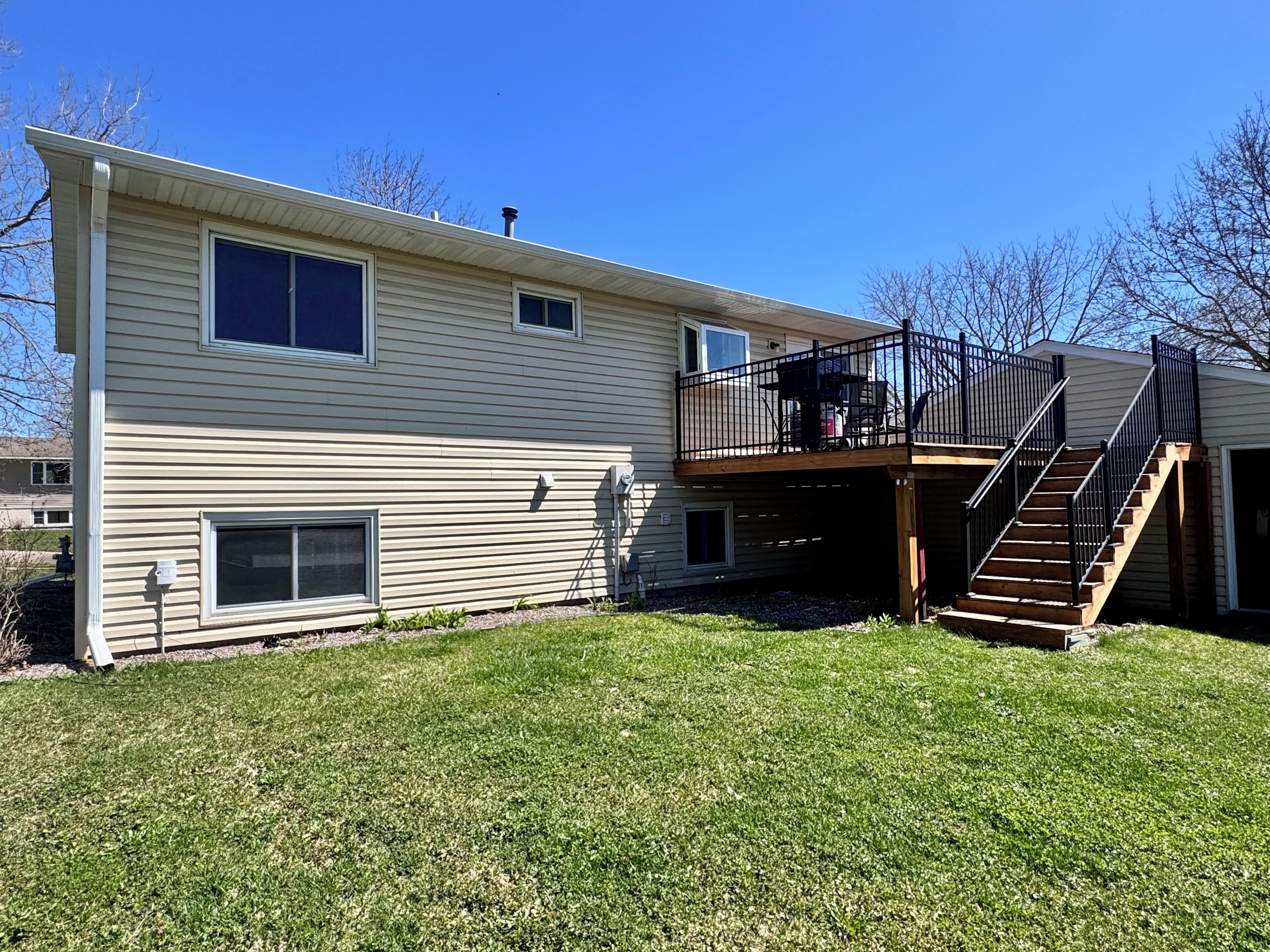 A two-story house with a balcony, a covered patio, and a staircase leading to the upper level.