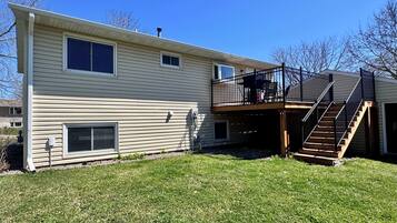 A two-story house with a balcony, a covered patio, and a staircase leading to the upper level.