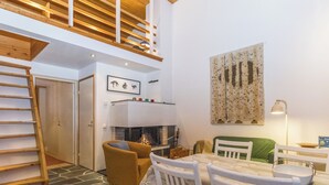 A modern interior with a wooden staircase, a fireplace, a dining area, and a green sofa. - Lupponen by Interhome (Inari)