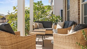 A covered patio with wicker furniture and a cushioned seating area. - New! Fig Tree House! Near Downtown, Hot Tub, 3 Kings, Pets/Family/Work Friendly (Greenville)