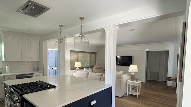Een moderne keuken met een centraal eiland, inbouwapparatuur en een eethoek met tafel en stoelen.