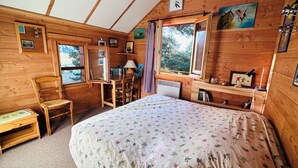 Une pièce chaleureuse, aménagée dans un chalet en bois, avec un lit, un bureau et une chaise.