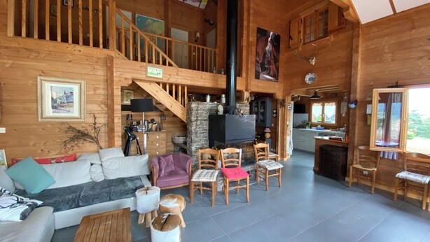 Une cabane en bois spacieuse comprenant un espace de vie, une cuisine et un escalier menant à un niveau supérieur.