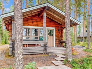 Une cabane en rondins dotée d’une véranda, de grandes fenêtres et d’une porte.