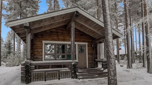 A log cabin with a wooden exterior, a front porch, and a window overlooking a snowy forest. - Luhtalemmikki by Interhome (Lieksa)