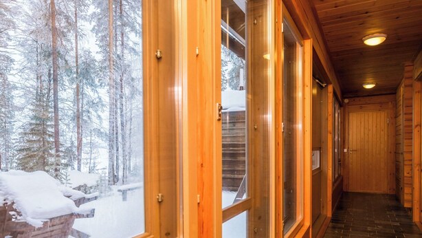 A wooden hallway with large windows and a view of a snowy forest. - Luhtalemmikki by Interhome (Lieksa)