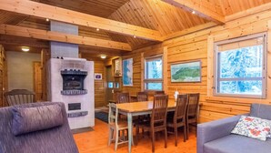 A wooden cabin interior with a dining area, a fireplace, and a sofa. - Luhtalemmikki by Interhome (Lieksa)