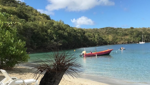 Ein Strand mit freiem Blick auf das Meer, ein rotes Boot und ein kleiner Steg.